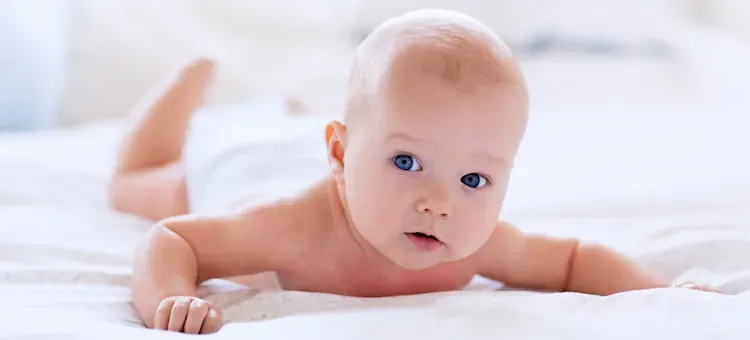 Niemowlę leżące na brzuchu, unoszące gł&oacute;wkę