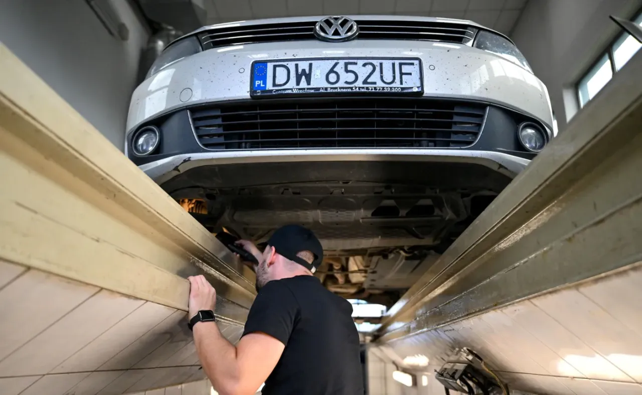 Mechanik dokonuje przeglądu auta Volkswagen na podnośniku, sprawdzając jego podwozie.