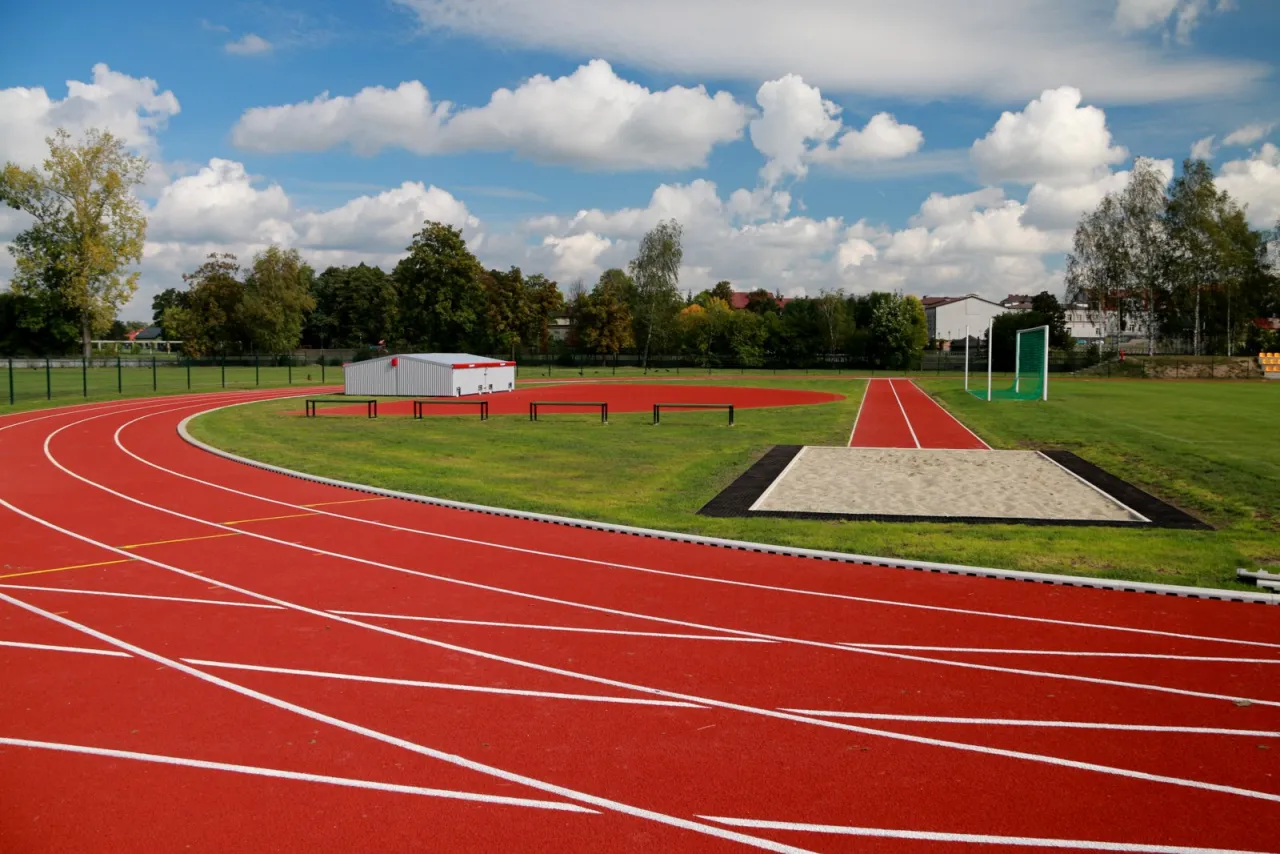 Stadion lekkoatletyczny z czerwonymi bieżniami i skocznią. Jedno okrążenie stadionu lekkoatletycznego ma 400 metrów.
