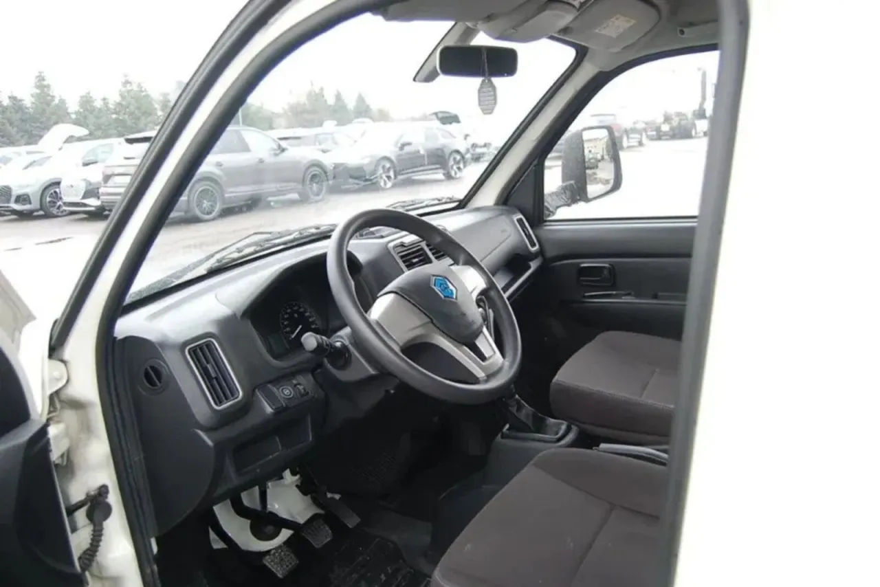 Wnętrze białego busa, idealnego jako jaki bus do transportu międzynarodowego. Widoczna kierownica, deska rozdzielcza i fotele.