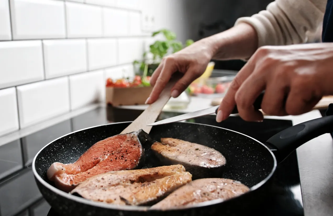 Smażenie ryb na patelni. W tle widać warzywa. Pytanie: na jakim tłuszczu smażyć ryby?