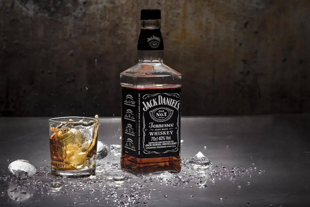 Butelka Jack Daniel's Tennessee Whiskey i szklanka z drinkiem. Różnica między whisky a whiskey oraz bourbonem a scotchem jest widoczna w procesie produkcji.