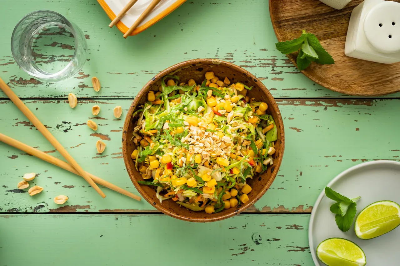 Kolorowa sałatka tajska z kurczakiem, kukurydzą i orzeszkami ziemnymi, gotowa do podania z pałeczkami.