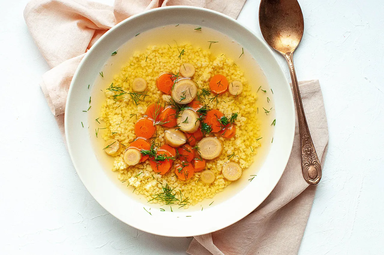 Wegański rosół na talerzu z warzywami i świeżymi ziołami