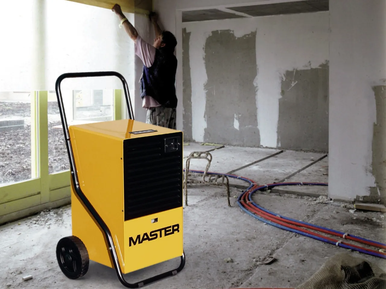 Osuszacz MASTER przyspiesza schnięcie gipsu na budowie. Pracownik mierzy wilgotność.