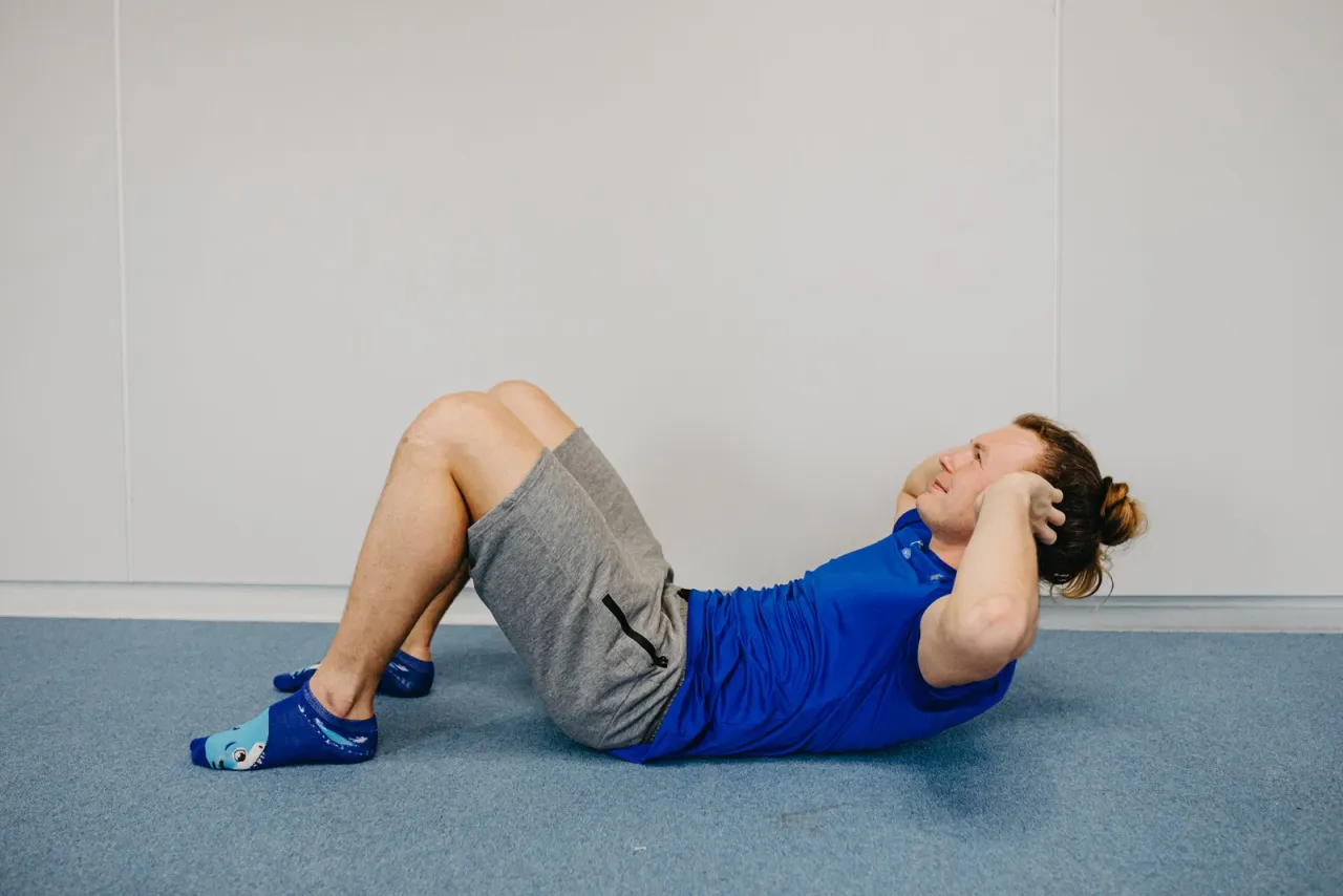 Osoba wykonująca brzuszki z złą techniką