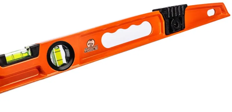 Glazurnik układa płytki z poziomicą i laserem, systemy poziomowania płytek