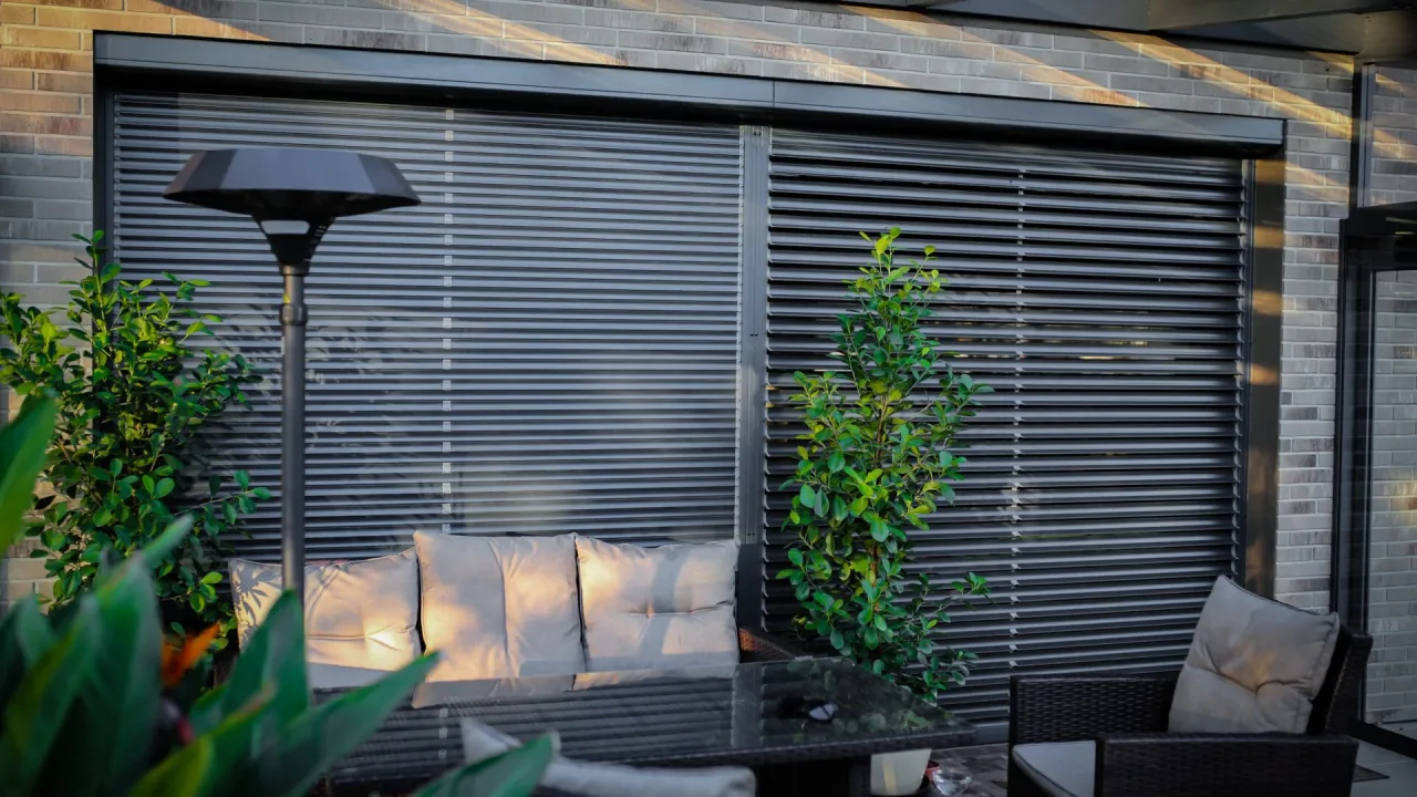 Nowoczesne żaluzje fasadowe zewnętrzne chronią taras. Wygodny wypoczynek wśród zieleni.