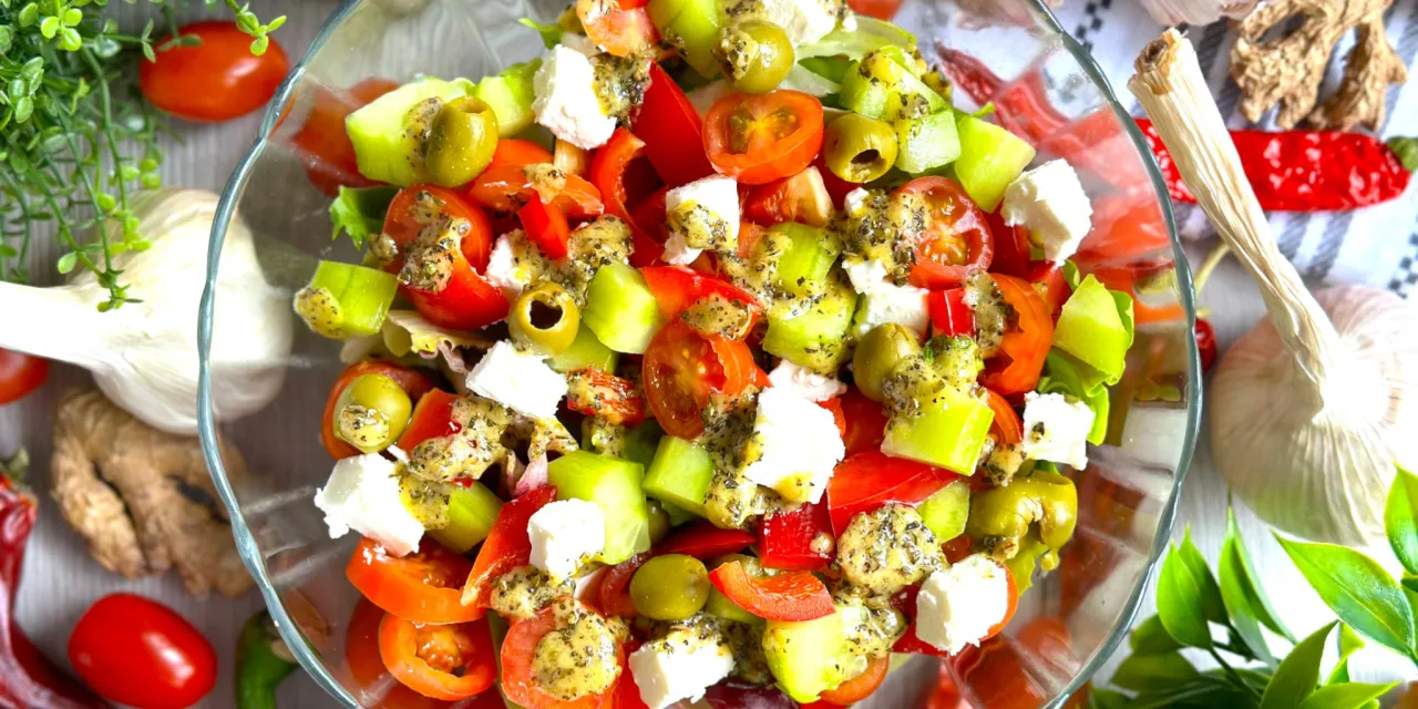 Sałatka grecka z fetą, pomidorami, og&oacute;rkiem i oliwkami, polana sosem. Idealny ser do sałatki greckiej to właśnie feta!
