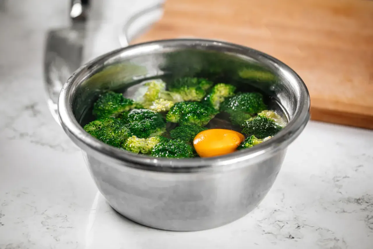 Brokuły w misce z wodą, gotowe do blanszowania. Obok żółta cytryna.