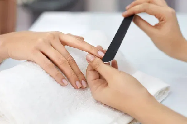 Zdjęcie dłoni z manicure w naturalnej pozie z rekwizytem