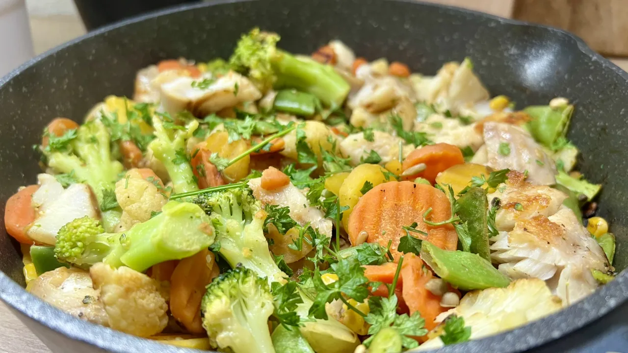 Pyszny obiad low carb: kawałki ryby z brokułami, kalafiorem, marchewką i fasolką szparagową, posypane natką pietruszki.