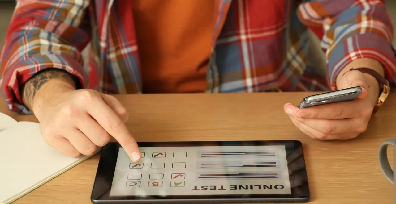 Osoba wypełniająca test online, skupiona, laptop, długopis