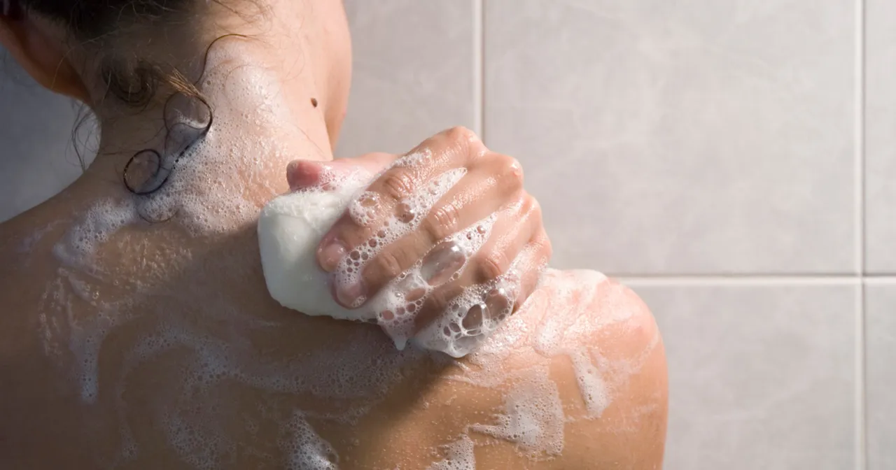 kobieta spłukująca peeling pod prysznicem