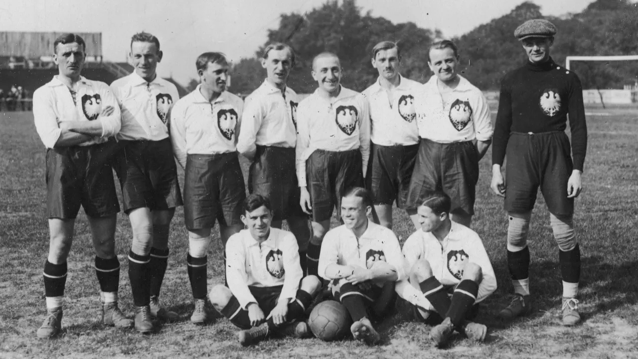 Drużyna piłkarska w historycznych strojach, z orłem na piersi. Zdjęcie przypomina, kiedy powstała piłka nożna i jak wyglądała gra.