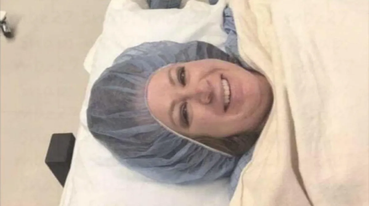 Kobieta rodząca w szpitalu, wspierana przez partnera, z uśmiechem