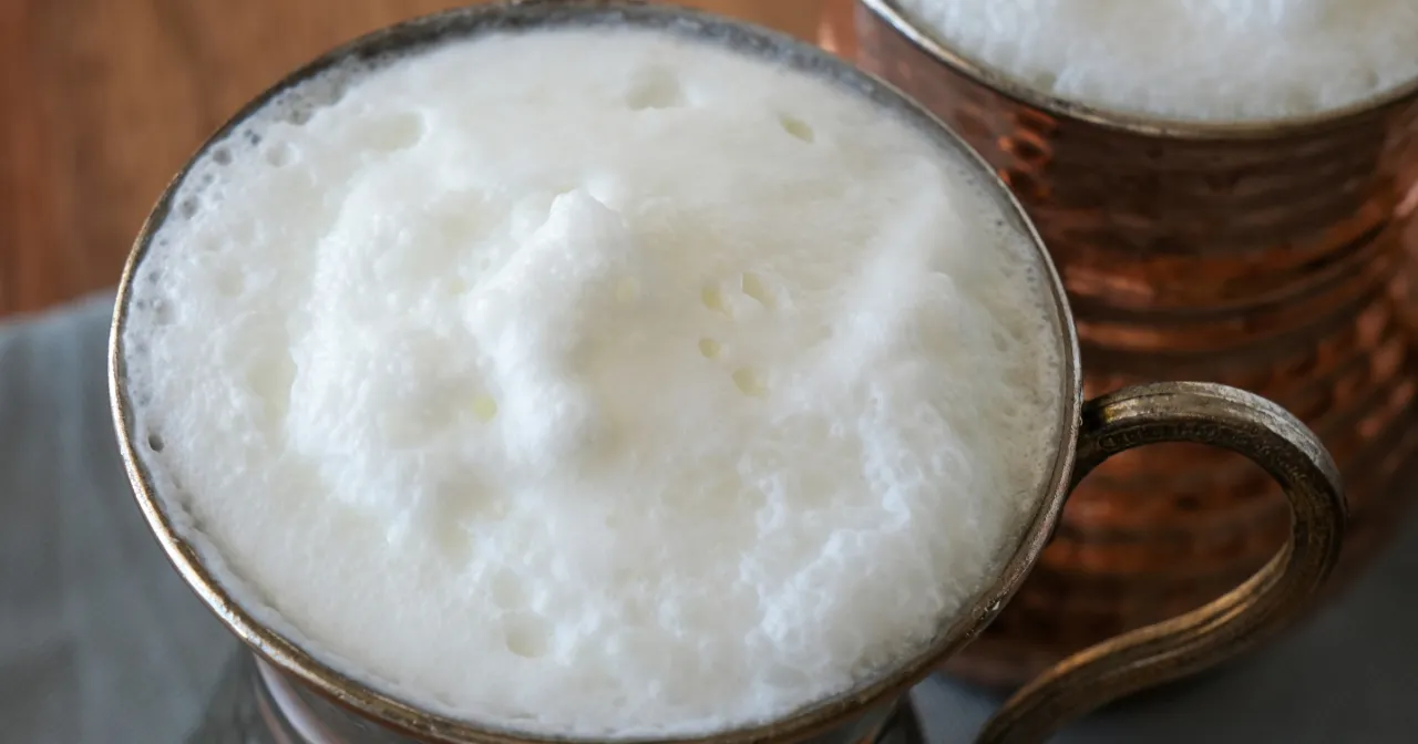 Puszysty ajran w miedzianym kubku. Czy ajran jest zdrowy? Tak, to orzeźwiający napój mleczny.