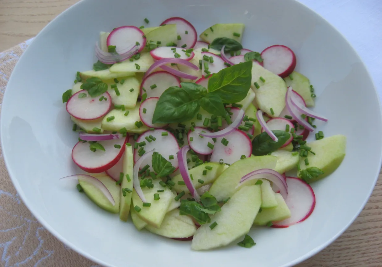 Orzeźwiająca surówka z rzodkiewki, jabłka i czerwonej cebuli, posypana szczypiorkiem i listkami bazylii. Idealna do obiadu.