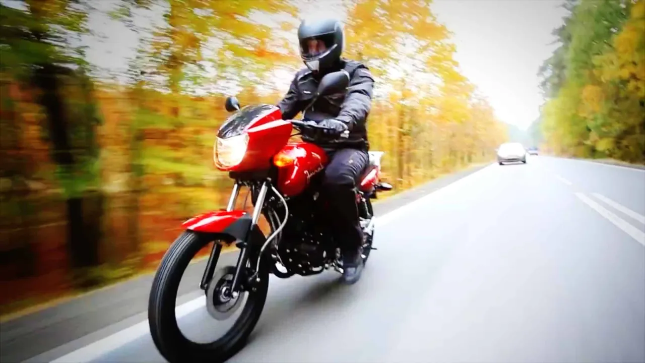 Czerwony motor mknie po drodze wśród jesiennych drzew. Zastanawiasz się, jakim motorem można jeździć bez prawa jazdy?