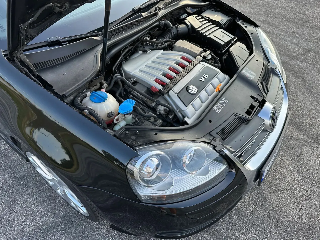 Czarny Golf R32 z otwartą maską, widoczny potężny silnik V6.