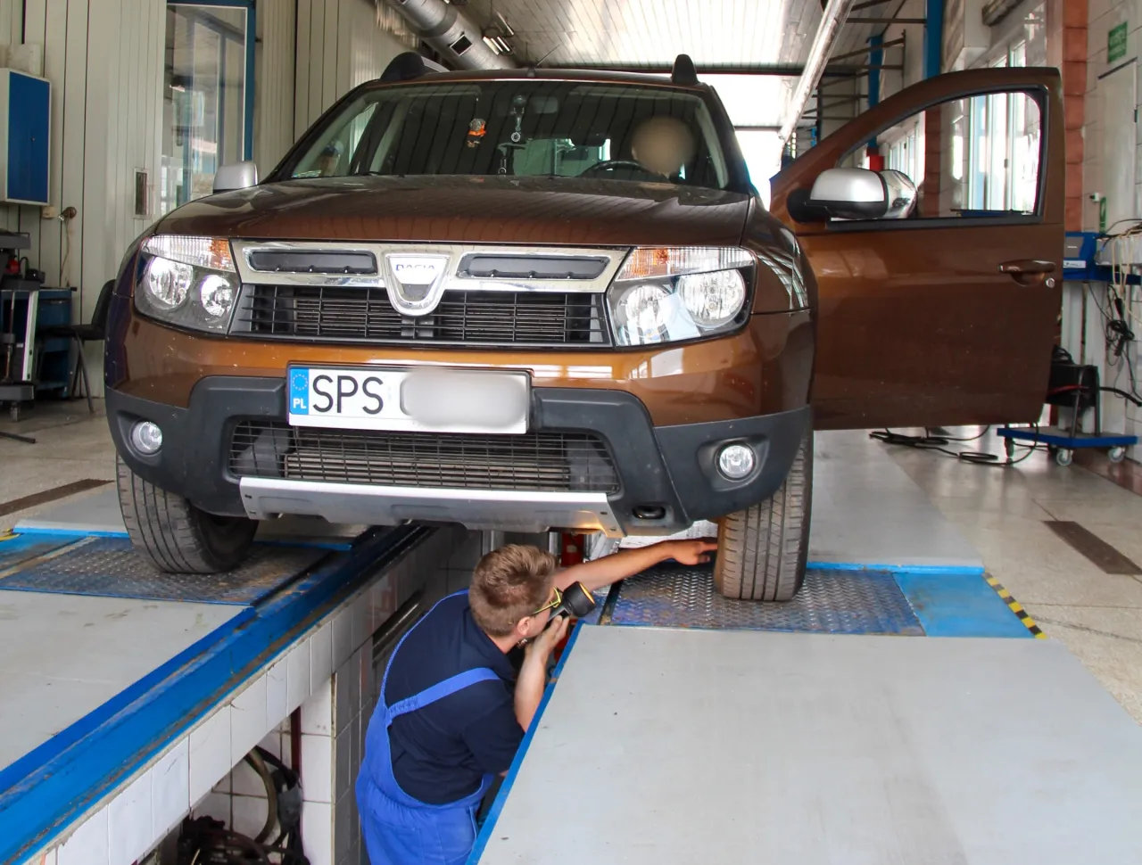 diagnosta sprawdza samoch&oacute;d na stacji kontroli pojazd&oacute;w