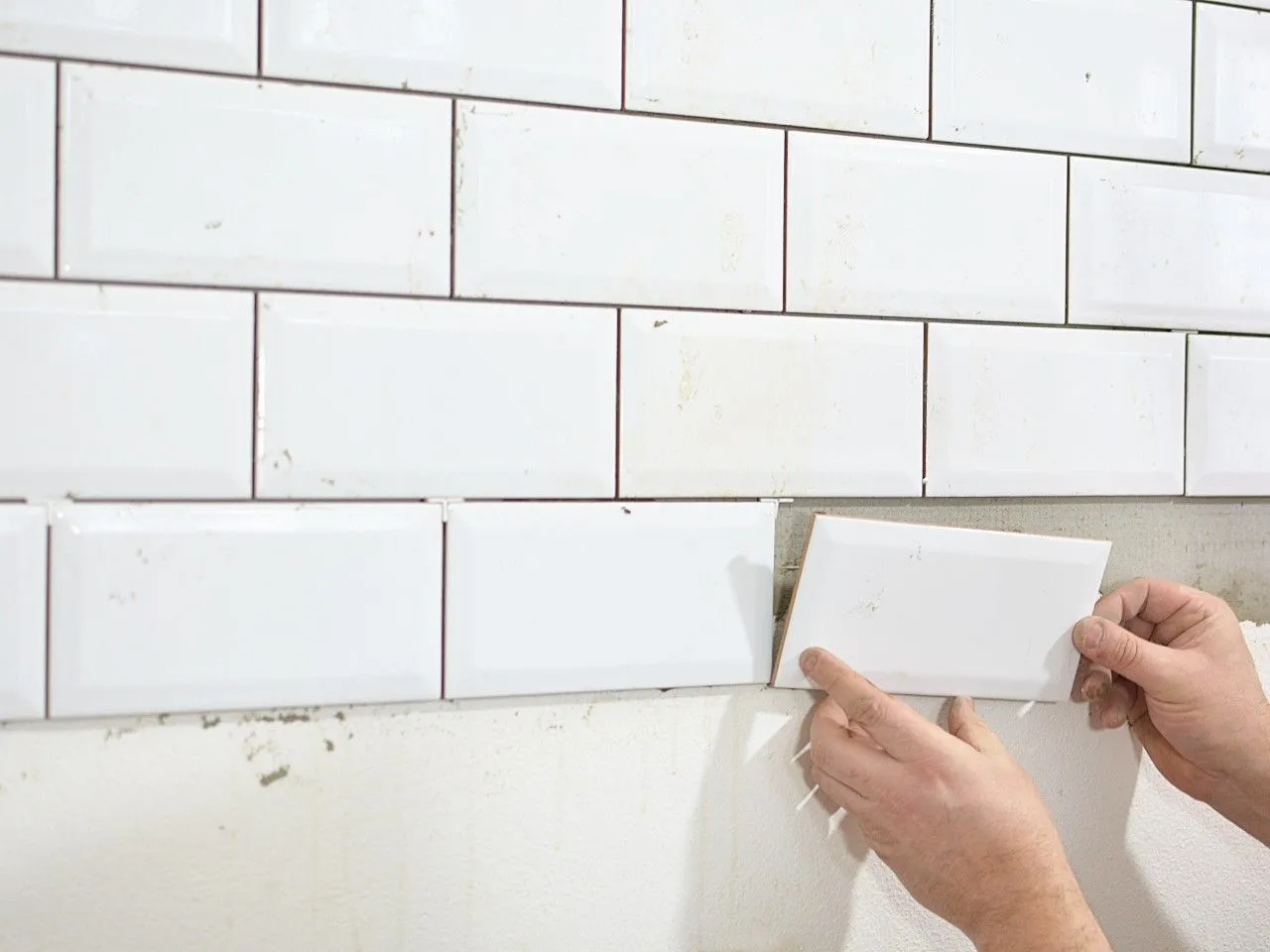 Układanie białych, dekoracyjnych płytek na ścianie. Zastanawiasz się, jaki klej do płytek gipsowych dekoracyjnych będzie najlepszy?