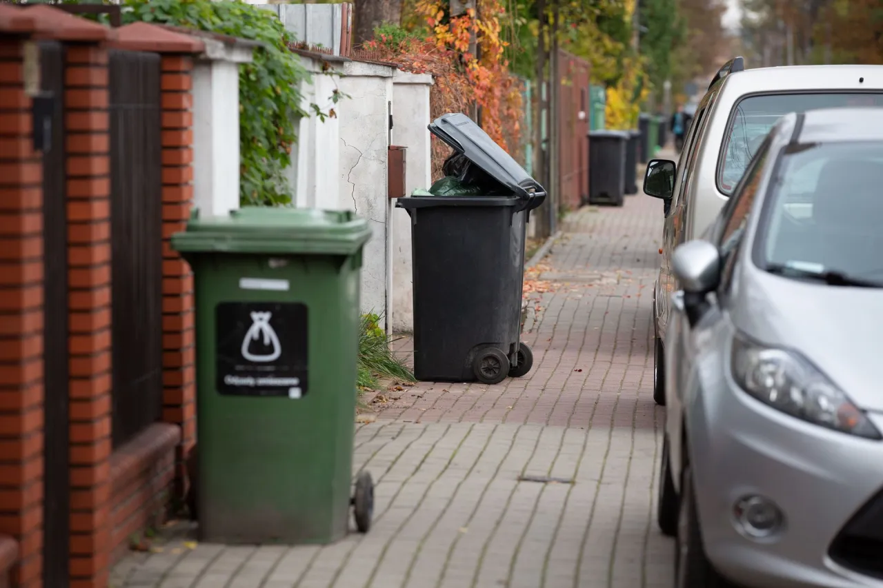 Zielony i czarny kosz na śmieci stoją przy ulicy. Zastanawiasz się, ile za śmieci w Zgierzu?