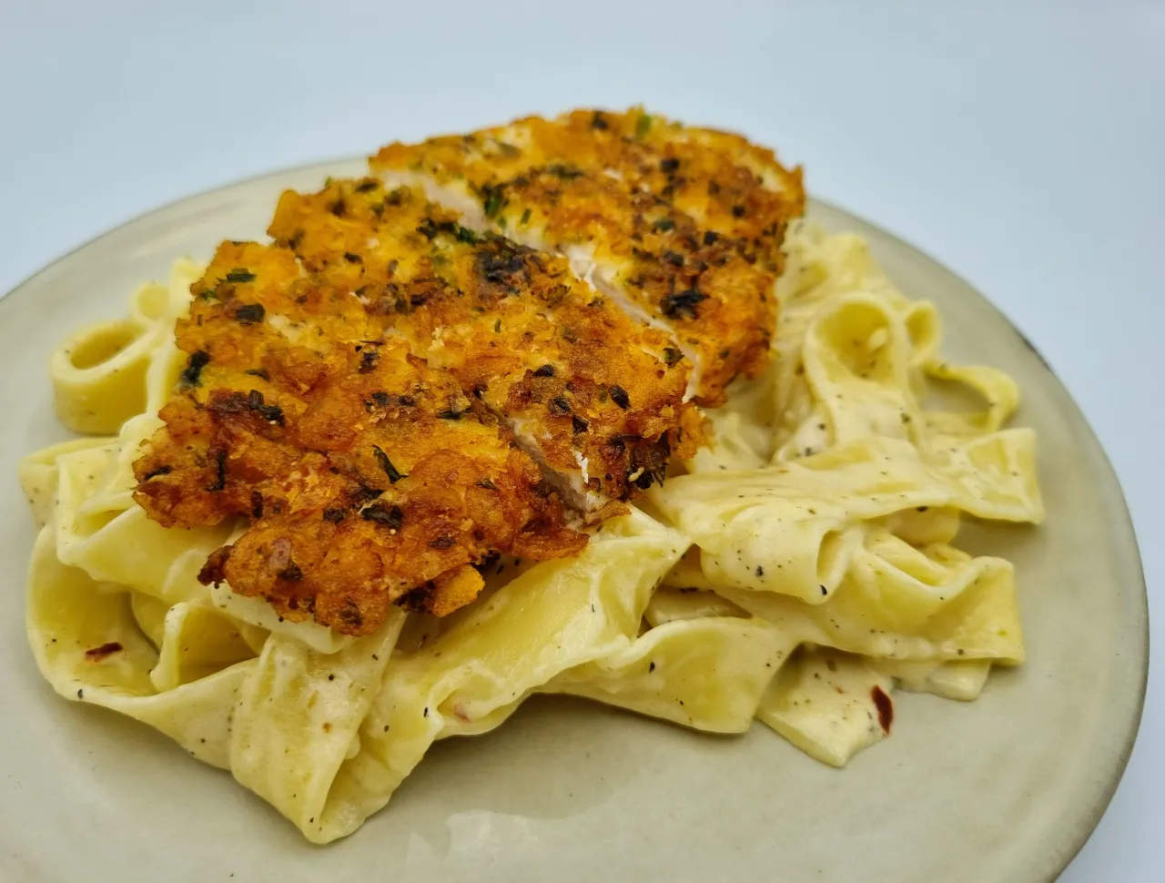 Pyszny makaron z kremowym sosem i chrupiącym kurczakiem w panierce. Idealny obiad dla każdego.