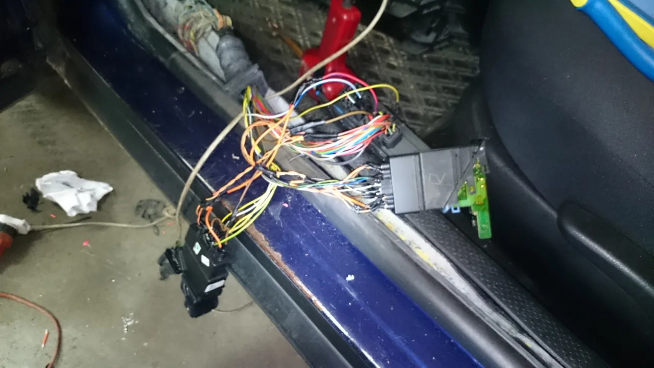 Wiązka przewod&oacute;w i sterownik centralnego zamka Passat B5, widoczne w progu drzwi, gotowe do montażu.