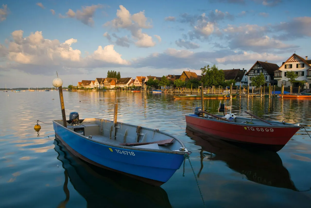 Dwie łodzie na spokojnym jeziorze, w tle malownicza zabudowa. To jedne z najpiękniejszych miejsc nad jeziorem Bodeńskim.