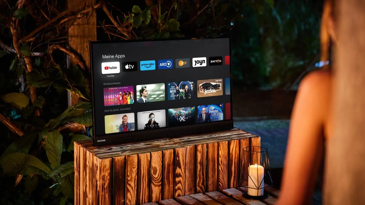 Person streamt Inhalte auf einem tragbaren Smart TV im Freien