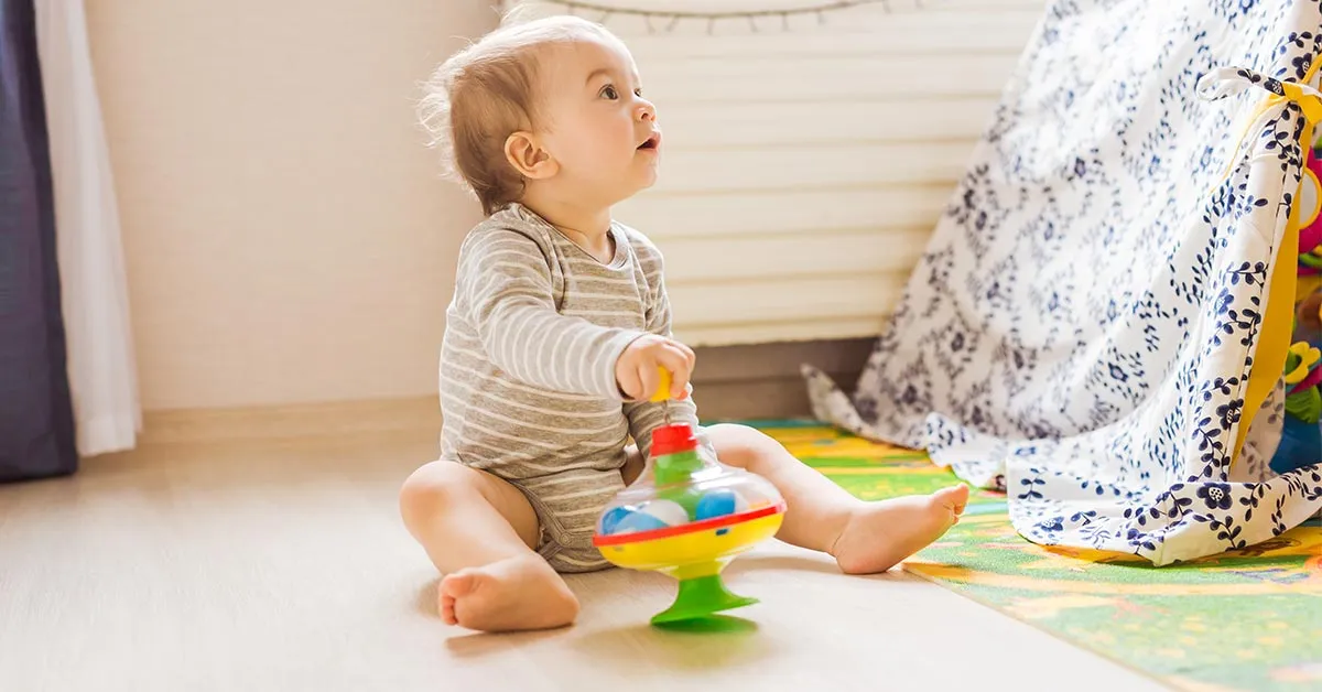 niemowlę bawiące się zabawkami na macie edukacyjnej