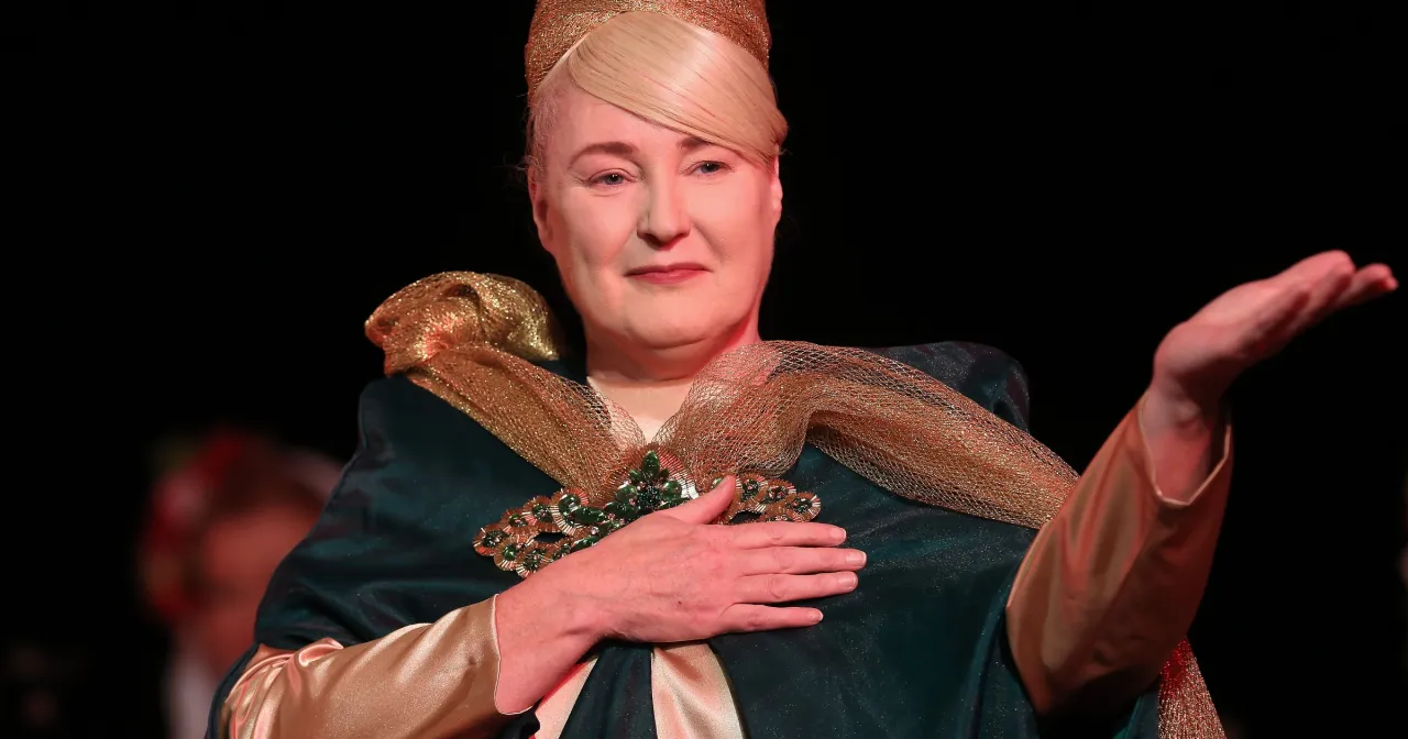 Kobieta w złotej koronie i zielonej sukni, z broszą, śpiewa w teatrze. Czy to gladiator muzyka?