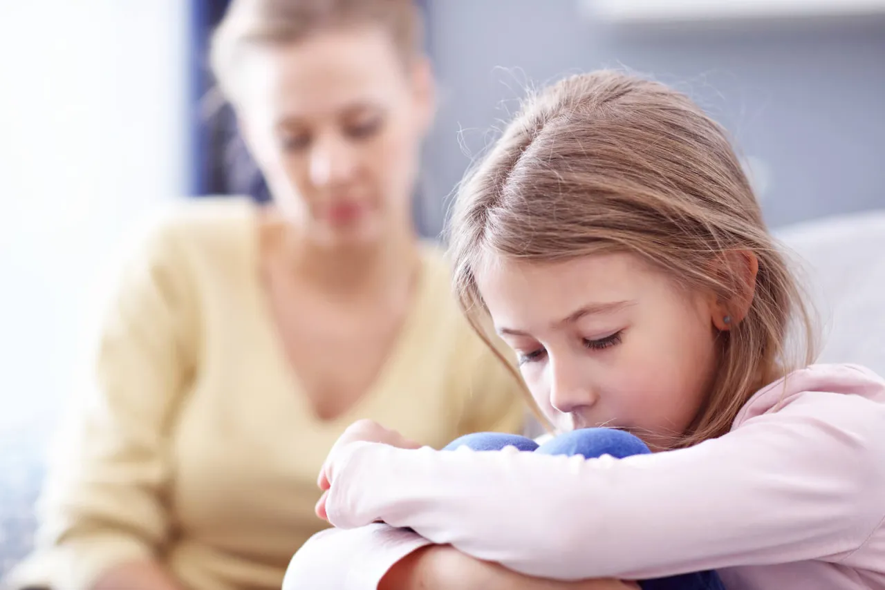 Dziecko siedzące samotnie, zamyślone, symbolizujące odrzucenie