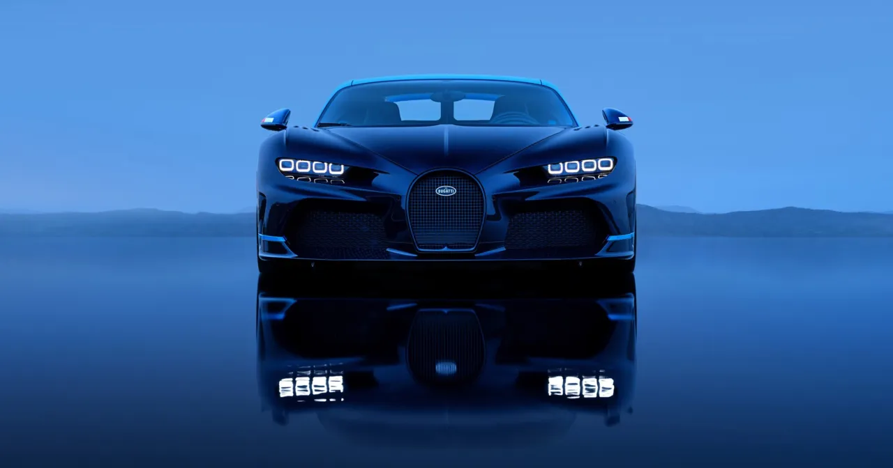 Ciemnoniebieski Bugatti Chiron na tle błękitnego nieba i gór. Kto ma w Polsce taki samochód?