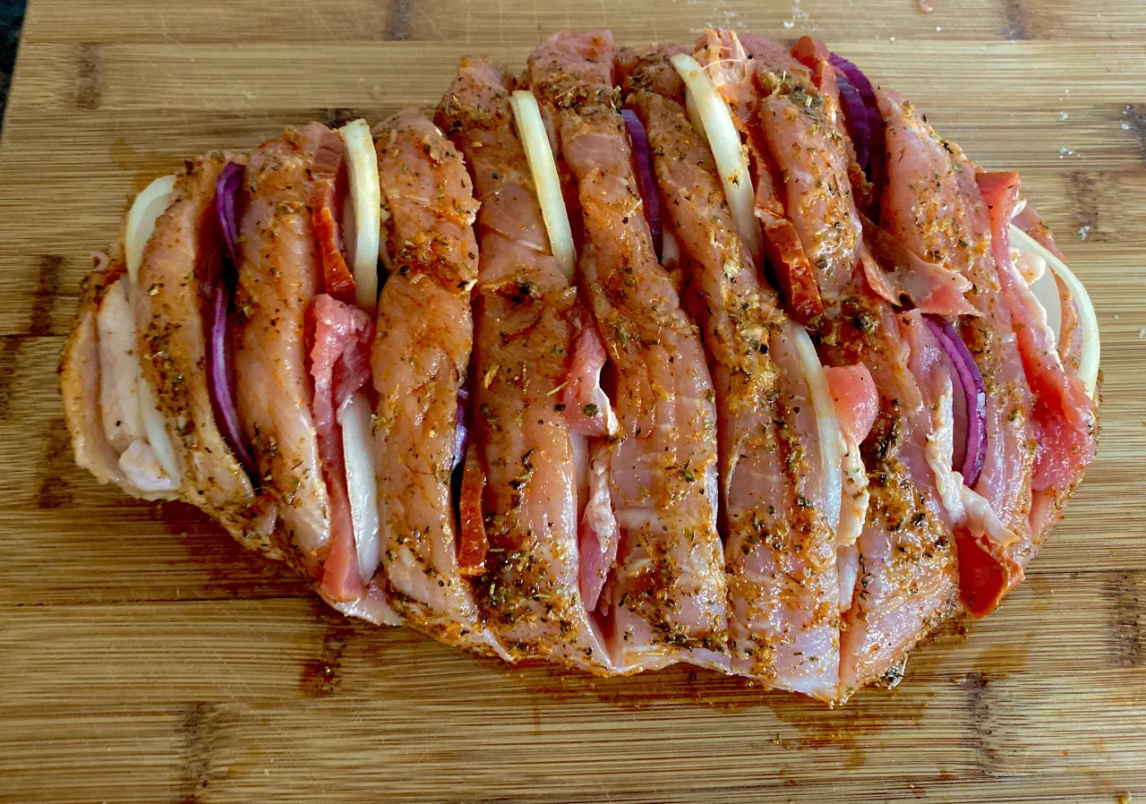 Przygotowana szynka wieprzowa z cebulą i przyprawami, idealna do pieczenia. Pytanie: co ugotować z szynki wieprzowej?