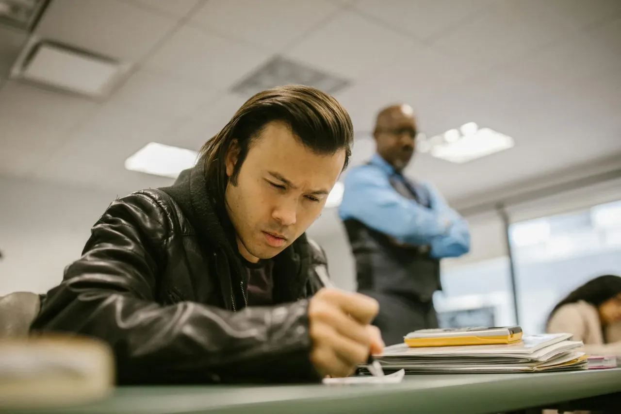 Dziecko rozwiązujące test w klasie pod nadzorem nauczyciela