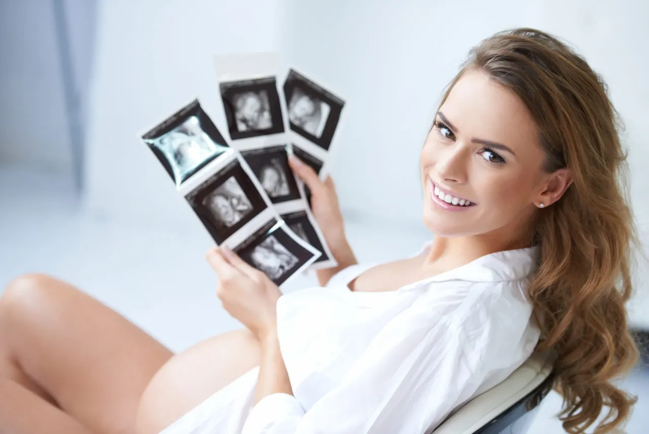 kobieta w ciąży trzymająca wyniki badań krwi z uśmiechem