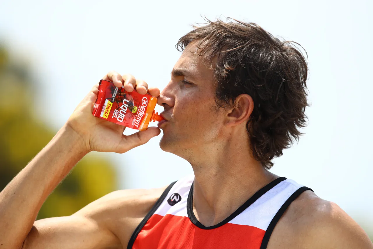 Biegacz pije napój izotoniczny podczas biegu