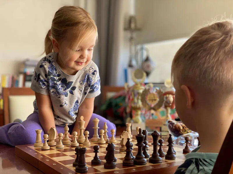 dziecko grające w szachy z książką