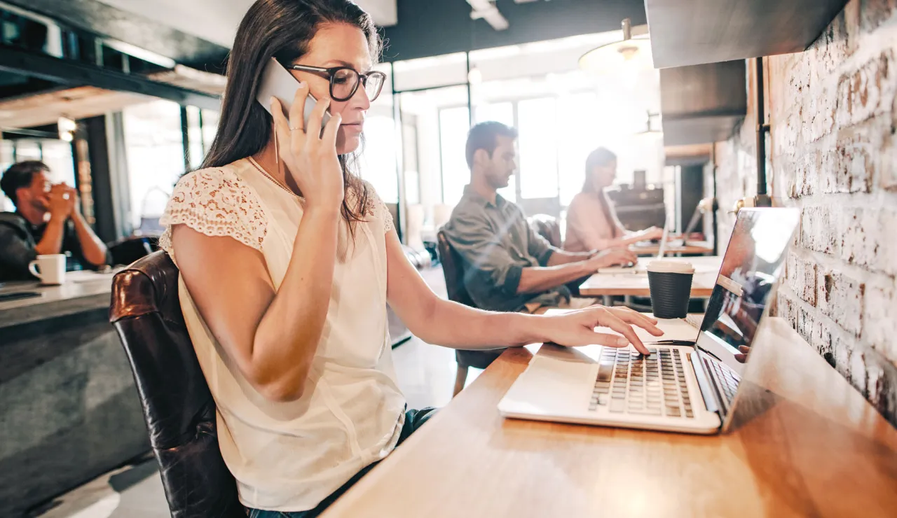 osoba pracująca na laptopie w kawiarni