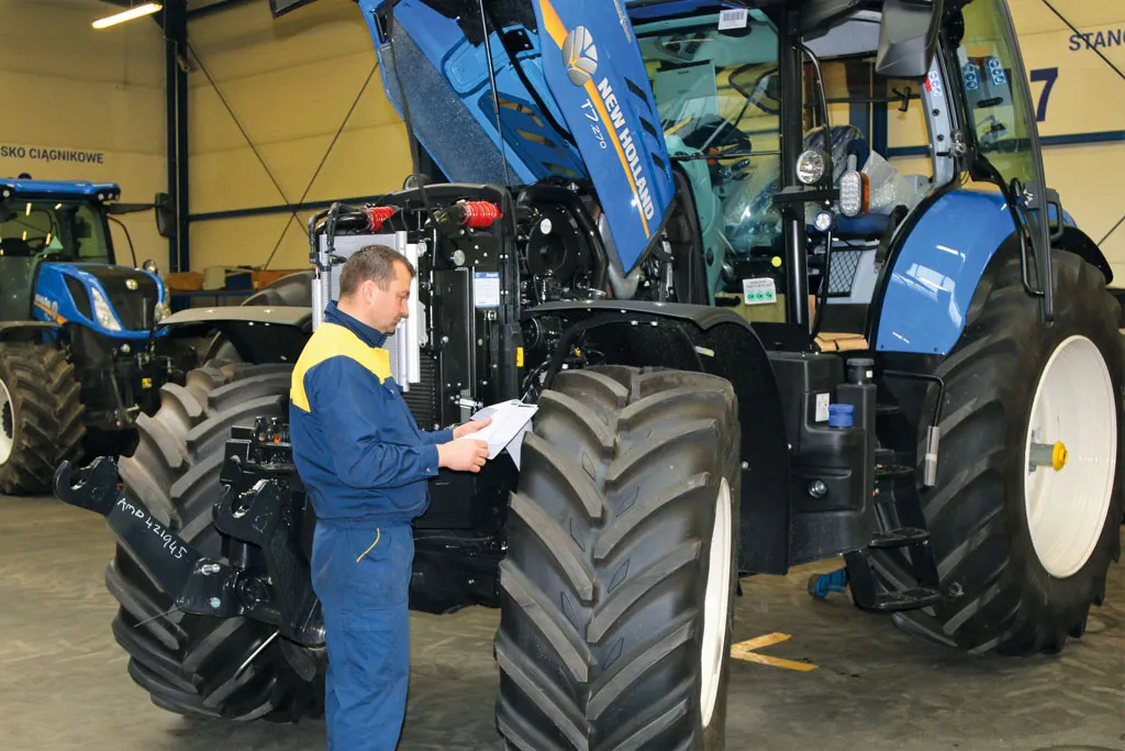 Rolnik sprawdzający opony w ciągniku przed przeglądem