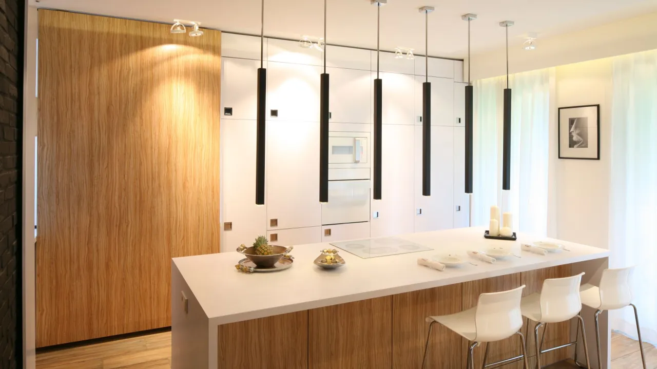 Nowoczesna kuchnia z wyspą. Cztery czarne lampy wiszące tworzą stylowe jakie oświetlenie nad wyspą kuchenną.