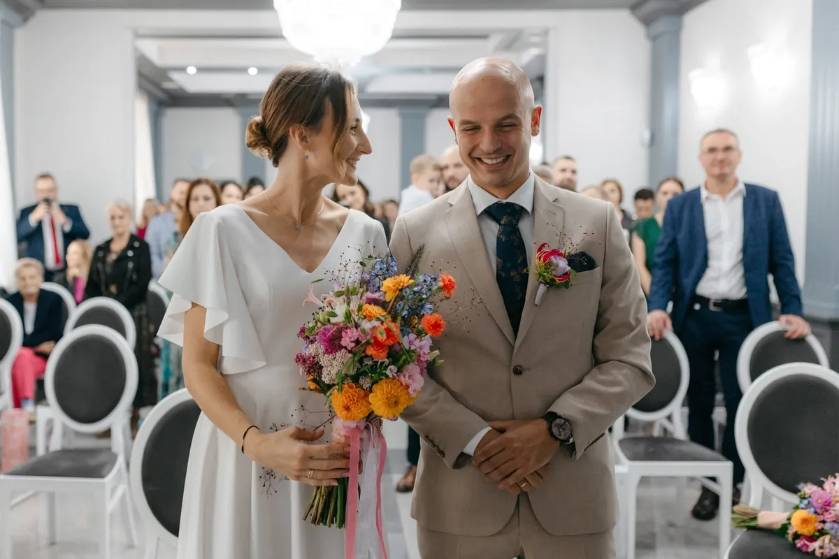 Szczęśliwa para młoda z bukietem. Zastanawiasz się, o co pytać fotografa na wesele?