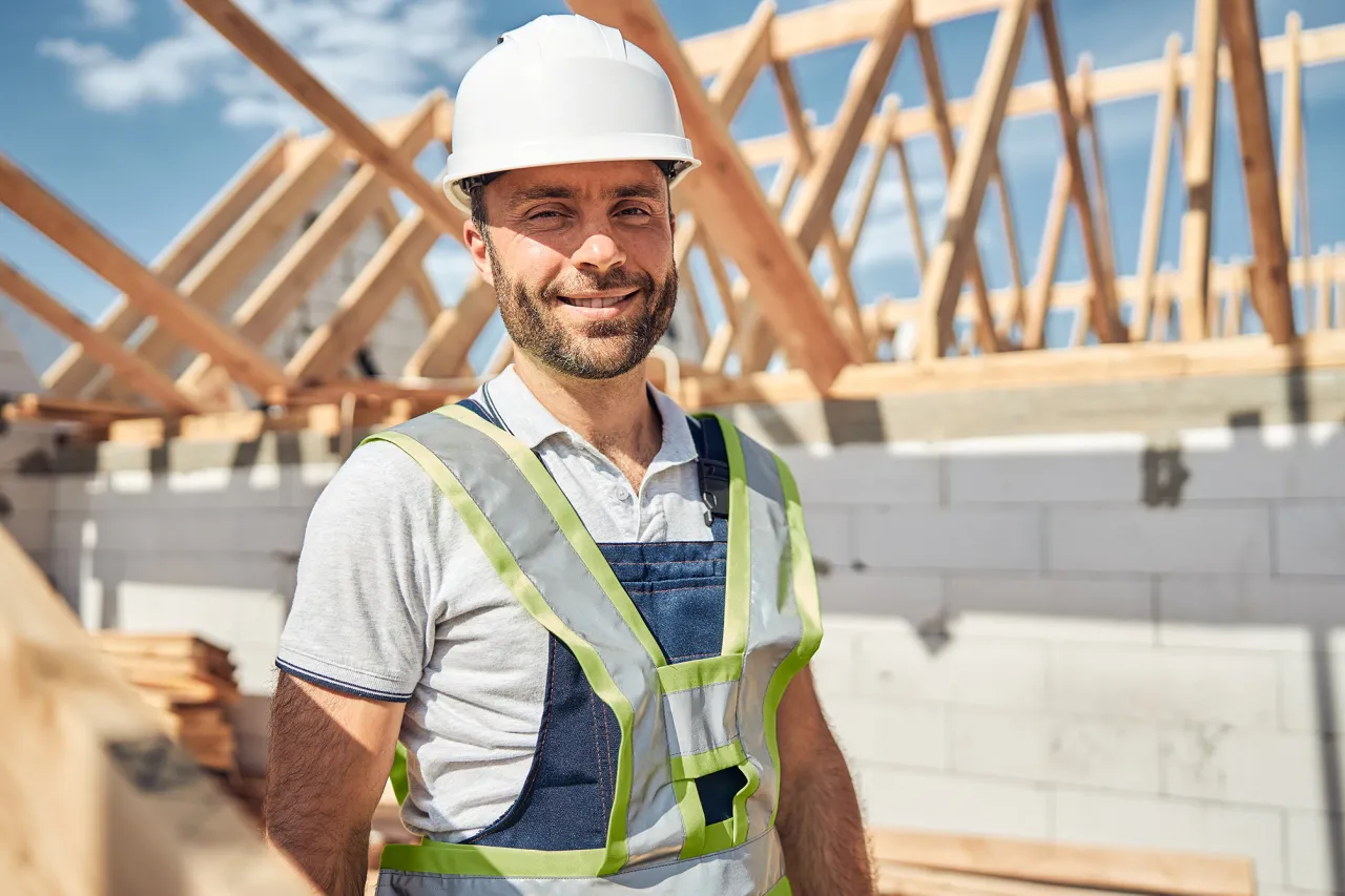 Budowlaniec w kasku na placu budowy domu. Zastanawiasz się, ile kosztuje budowa domu 150m2?