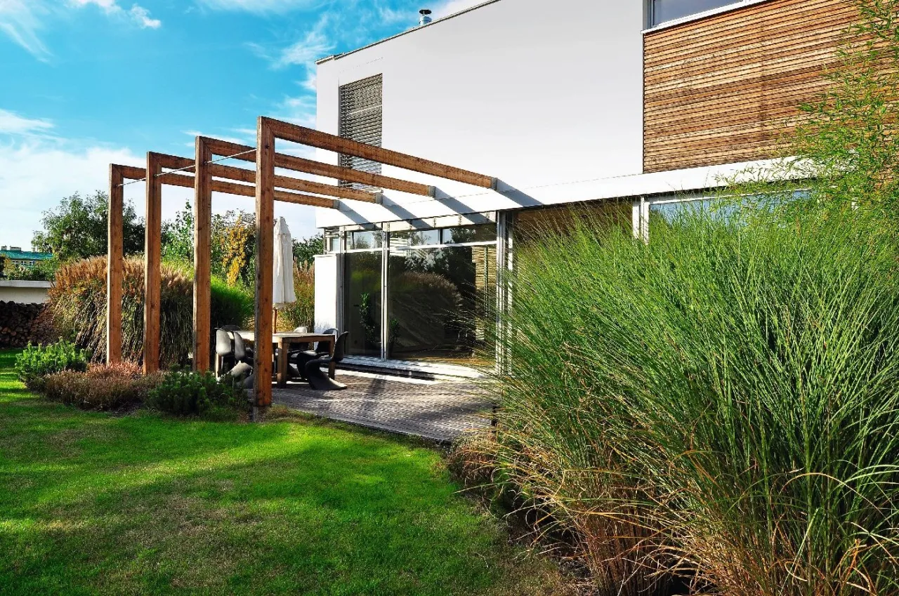 Drewniana pergola nad tarasem z meblami ogrodowymi. Inspiracja, jak zbudować pergolę, by stworzyć przytulne miejsce relaksu.