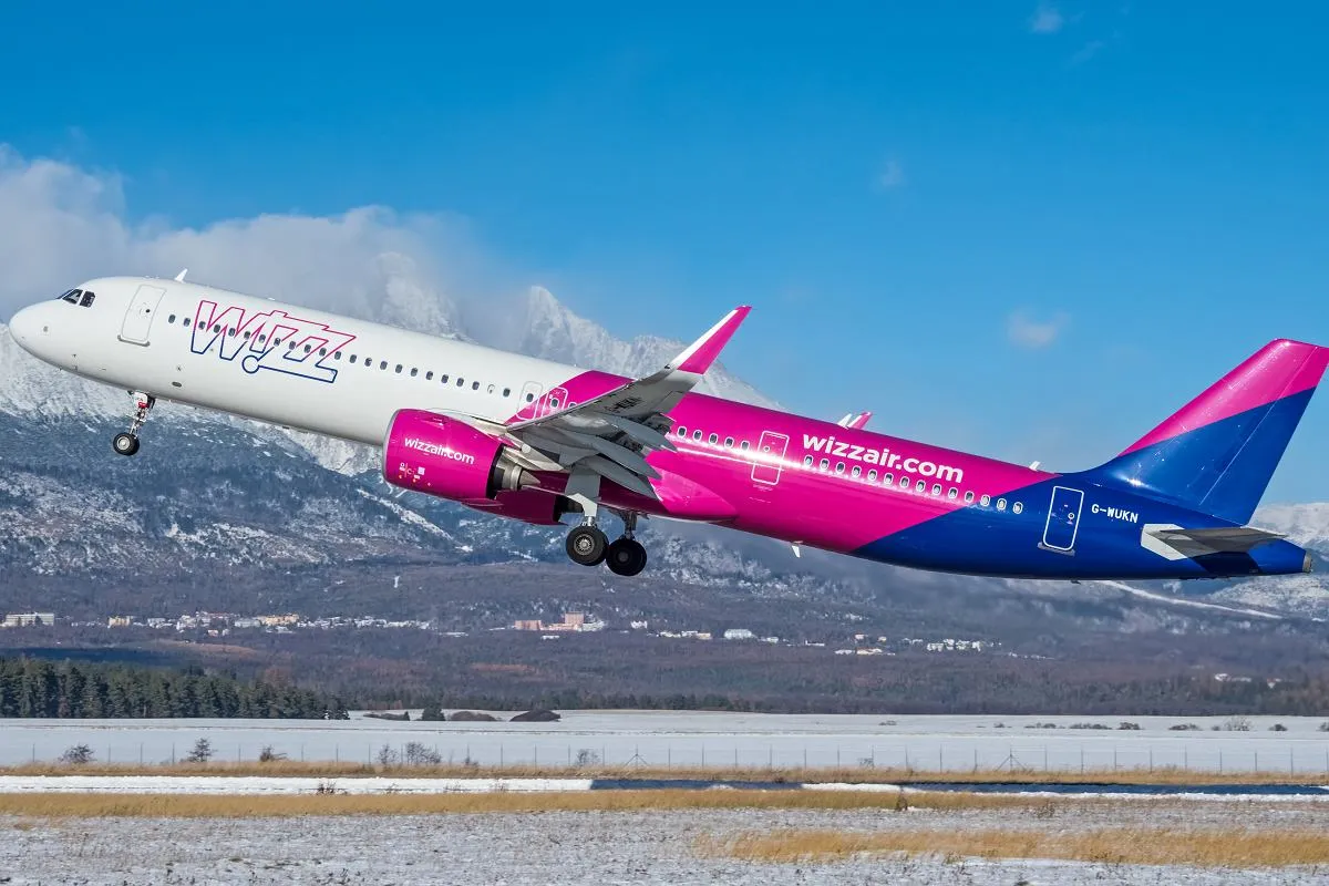 Samolot Wizz Air startuje na tle g&oacute;r. Wizz Air to tania linia lotnicza, kt&oacute;ra oferuje loty po Europie.