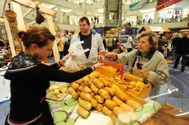 Turysta kupujący oscypki od bacy, tradycyjny str&oacute;j g&oacute;ralski