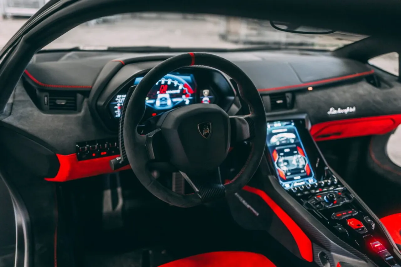 Wnętrze Lamborghini Centenario, z czerwonymi akcentami i cyfrowym kokpitem. Zastanawiasz się, ile kosztuje lamborghini centenario?