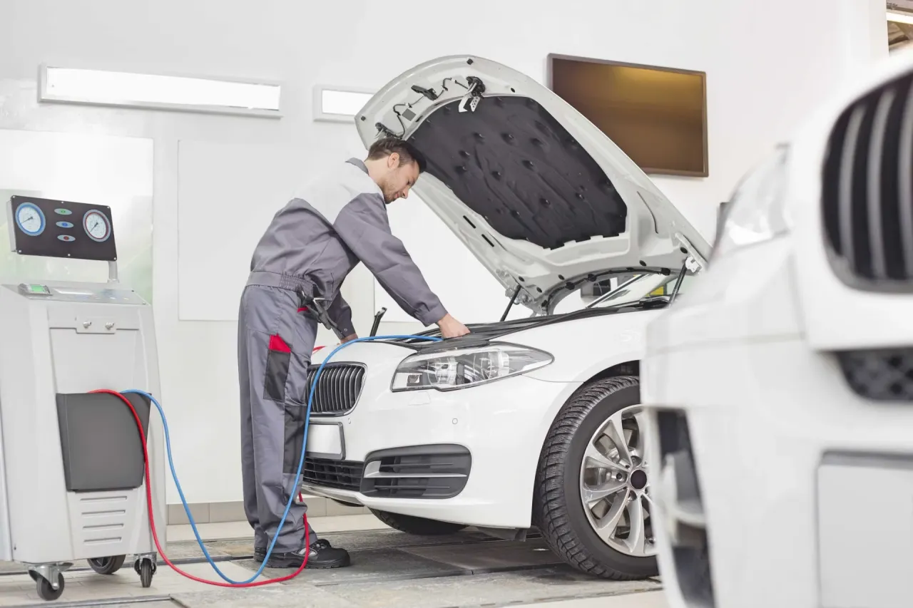 Mechanik sprawdza auto, zastanawiasz się, ile kosztuje przegląd samochodowy? Na zdjęciu widać serwis.